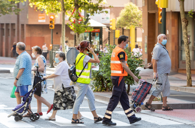 Un trabajador social, acompañado por personal de protección civil, preparados para realizar visitas domiciliarias en el barrio zaragozano de Las Delicias en Zaragoza