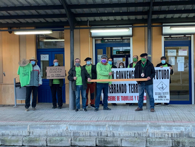 Mimebros de Cambiar Monzón celebrando este lunes la recuperación de la venta presencial de billetes en la taquilla de la estación.