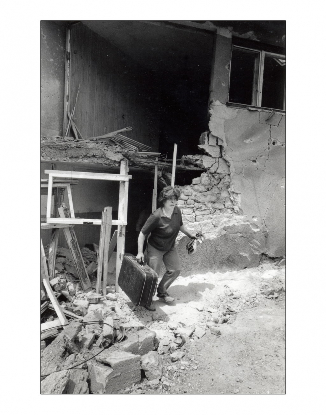 Sarajevo Una mujer sala de una casa alcanzada por un proyectil con una maleta y una tomatera