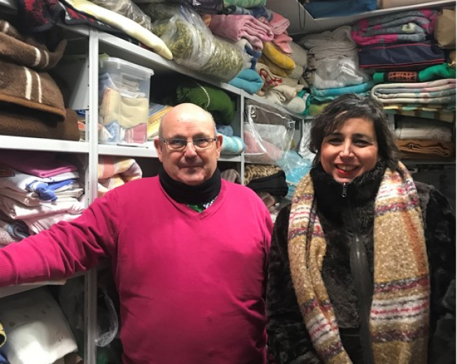 Antón Borraz, presidente del centro de San Blas, y una de las voluntarias, en el lugar donde se recogen las mantas para la campaña.