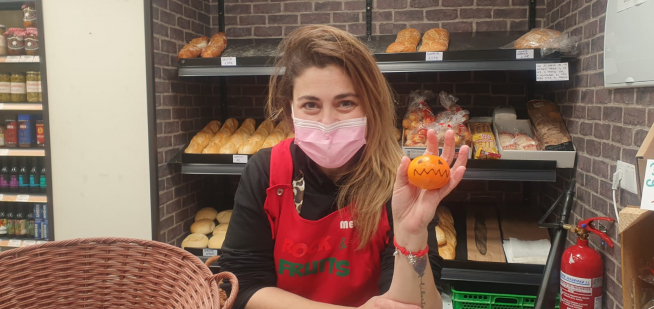 La propietaria de la frutería, con uno de los regalos que ofrece.