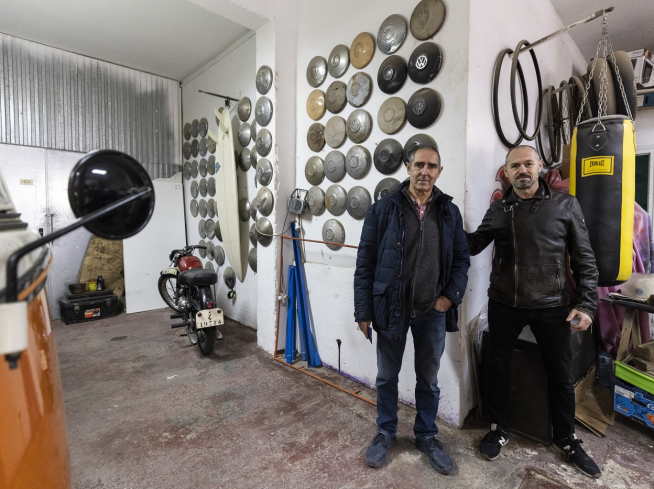 Alberto y su amigo mecánico Antonio Francés, con una colección de tapacubos de Volkswagen y un saco de boxeo.