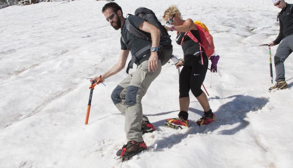 Dos montañeros equipados con piolet y crampones descienden el glaciar.