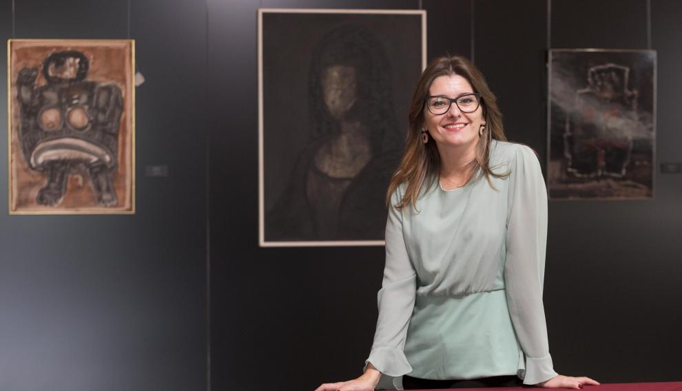 La periodista oscense Esther Puisac, junto a algunas de las obras de la exposición sobre Agustín Alamán que se pueden ver en el Casino de Huesca.