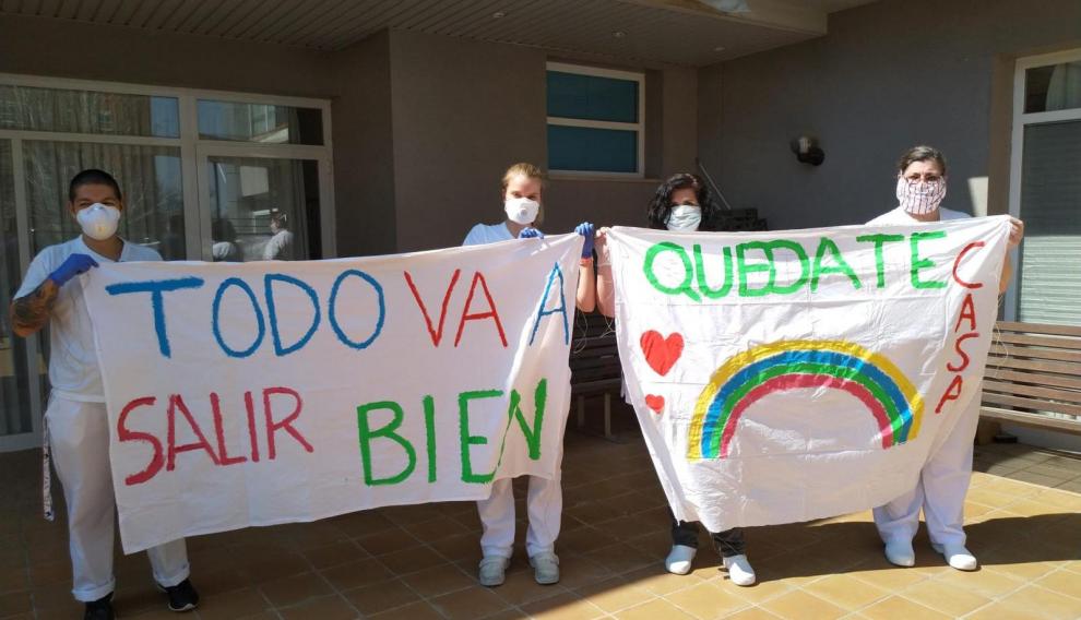 Gerocultoras que trabajan en el Centro Cai Afedaz con una pancarta animando a la gente a quedarse en casa.