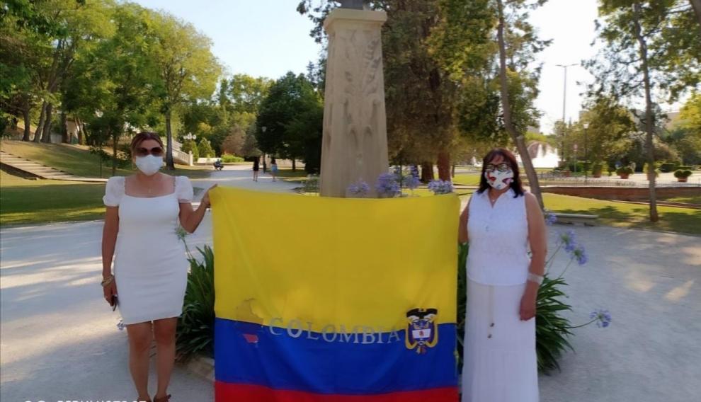 Pilar Sevilla (izquierda) con una bandera de Colombia junto al Monumento a Simón Bolívar en el parque José Antonio Labordeta, acompañada por  Luz Mary (vocal de la asociación).