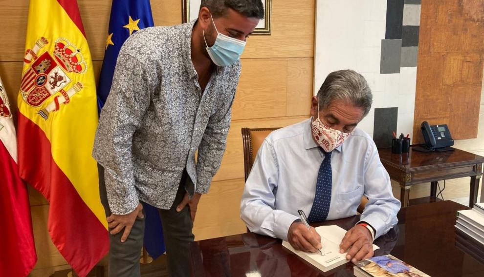 Miguel Ángel Revilla, firmando a Javier Pueyo uno de sus libros.