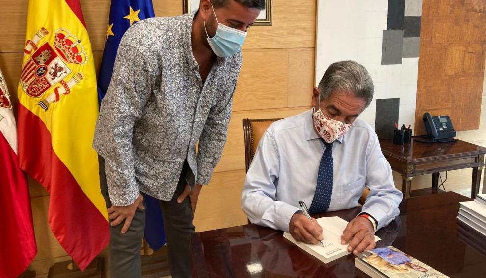 Miguel Ángel Revilla, firmando a Javier Pueyo uno de sus libros.