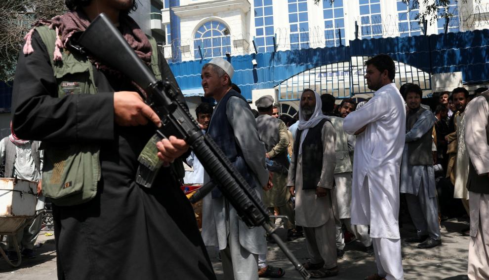 Un miembro de seguridad talibán vigila la fila de personas frente al Banco Azizi de Kabul, en Afganistán
