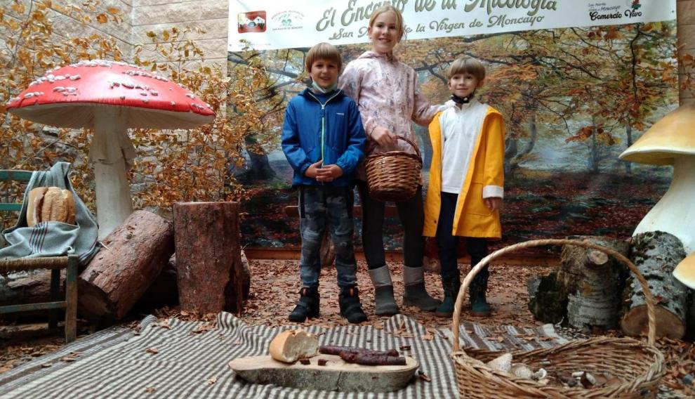 Tres jóvenes aficionados posan en el escenario micológico que se ha instalado este año