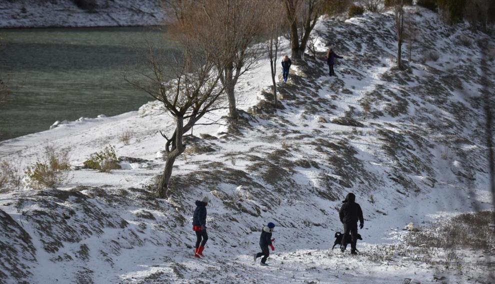 En Arguis, cerca de Huesca, hay quien ha madrugado para jugar con la fin capa de nieve que cubre los alrededores del embalse.