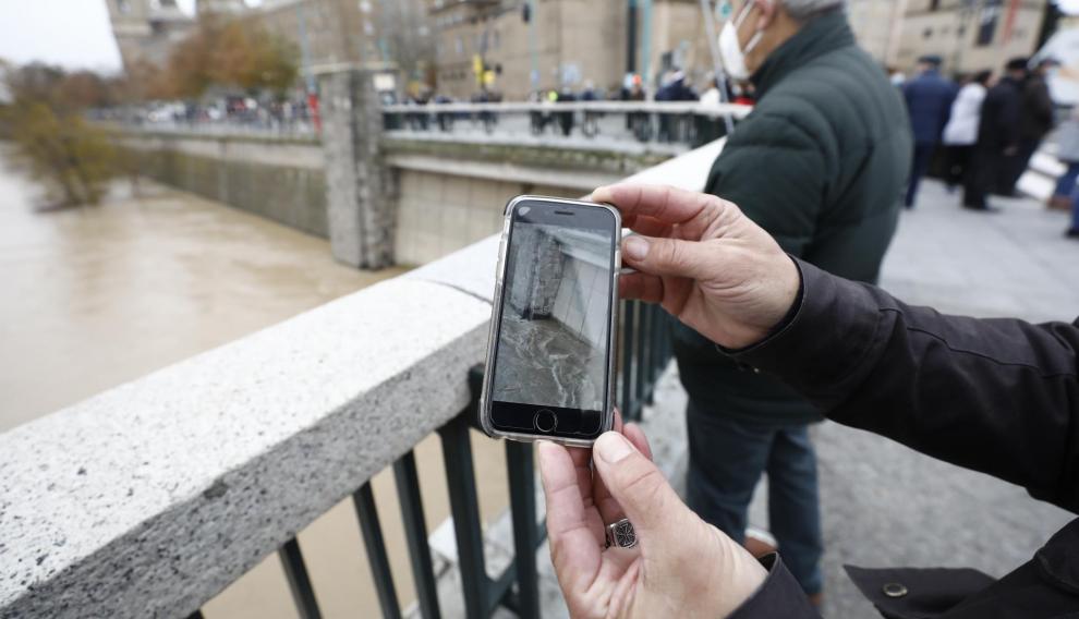 Un vecino de Zaragoza enseña en su teléfono móvil una fotografía que conserva de la anterior crecida extraordinaria, en 2015.