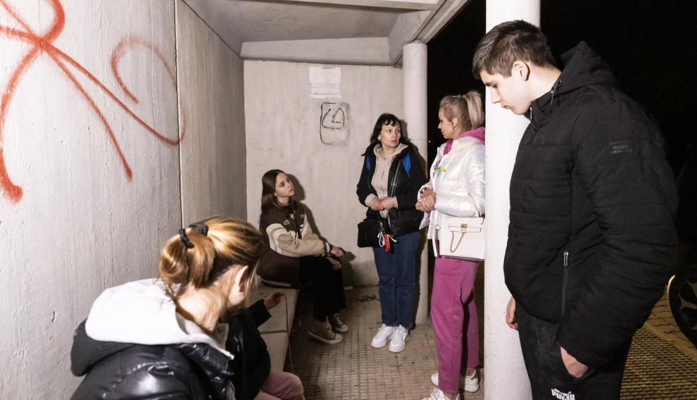 Anastasia Sukhuvyey, apoyada en la columna, charla con sus familiares y otros de los refugiados que llegaron en el avión militar en la parada de autobús.