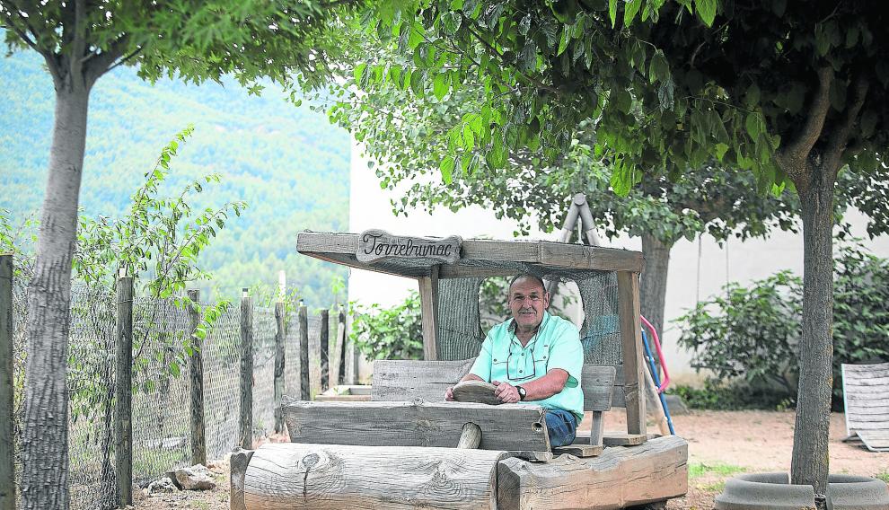 El fundador de Torrebruñac, José Román, en el troncomóvil a tamaño 'natural' que tiene en el jardín y que ha tallado él mismo.