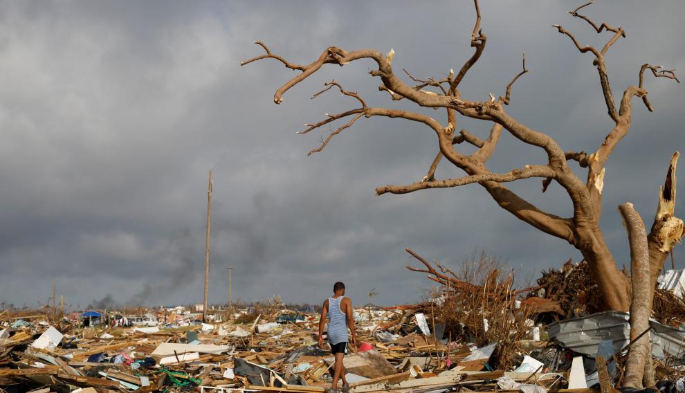 Un hombre anda sobre los restos de las viviendas arrasadas por Dorian en Bahamas