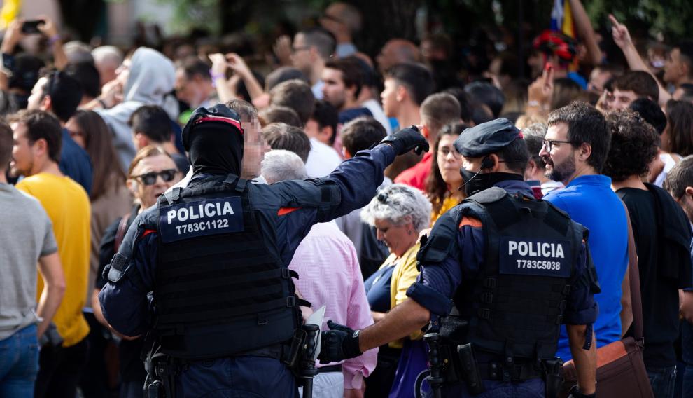 Los Mossos d'Esquadra controlan la multitud que se ha congregado junto al domicilio en el que se ha practicado un registro.