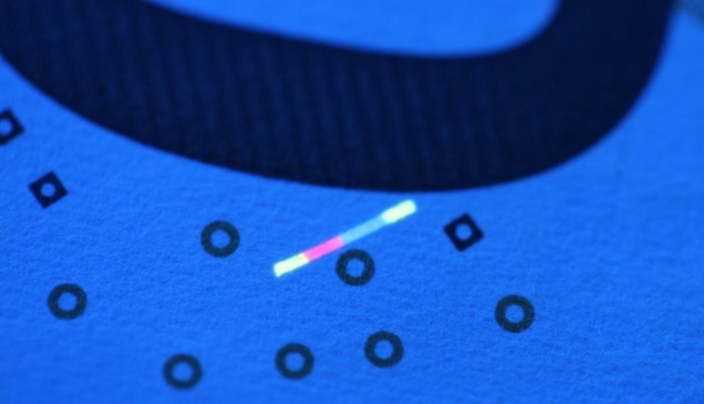 Inclusión fluorescente en un billete de 50 euros iluminado con luz ultravioleta de 365 nm. Tierras raras contra la falsificación.