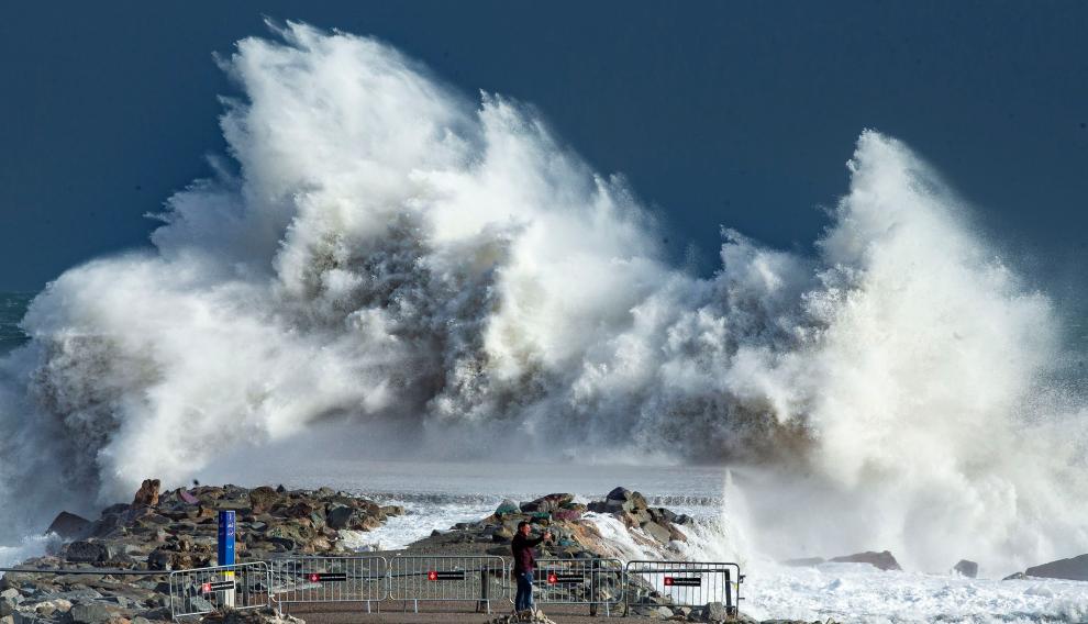 Una persona observa las impresionantes olas en la playa de Barceloneta, en Barcelona