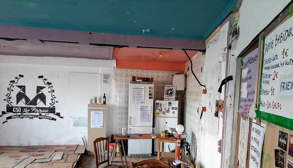 Salón reuniones con tabiques tirados y carteles anunciando venta bebidas en la casa desalojada.