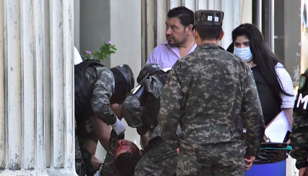 Varios compañeros sacan el cadáver de otro de los policías asesinados