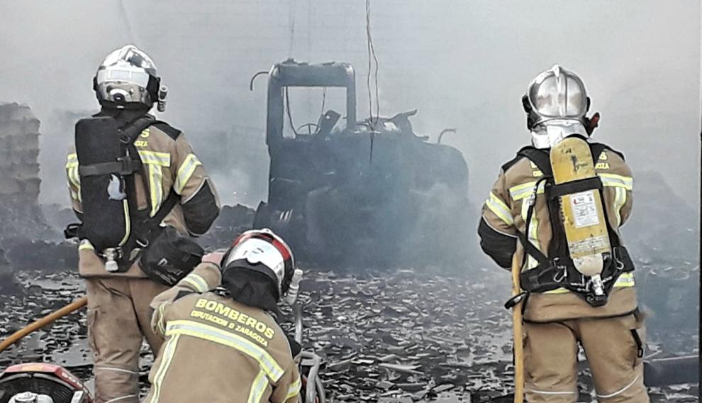 Tres bomberos de la DPZ frente a una máquina totalmente calcinada