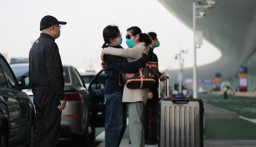 Traveller wearing a face mask hugs a woman outside Wuhan Tianhe International Airport in Wuhan