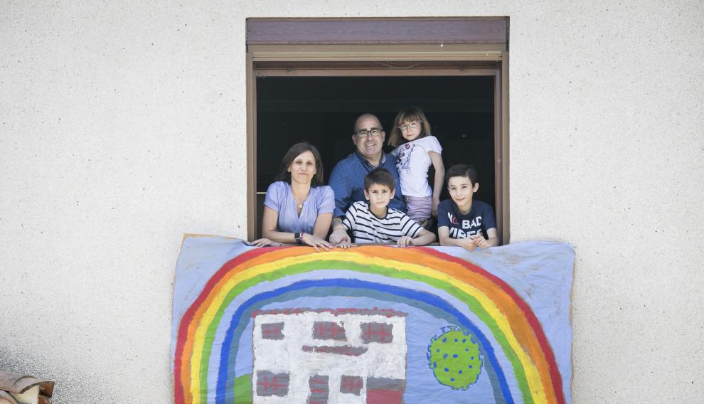 Víctor Laguna y Guayante Barrabés, en una ventana de su domicilio con sus hijos Marina (6 años), Nico (8) y Hugo (12).
