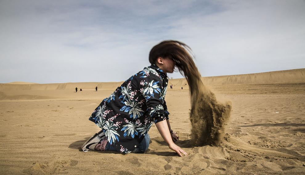 Mina desentierra su cabello de la arena en un juego con sus amigos lejos del control de la policía de la moral en Isfahan (Irán).