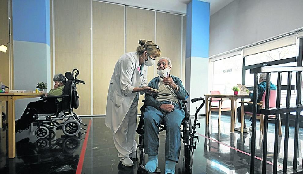 La terapeuta ocupacional ayuda a hacer una actividad a uno de los residentes