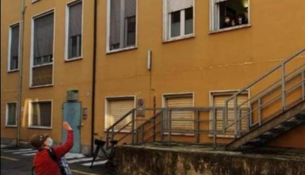 Stefano Bozzini, de 81 años, saluda a su esposa, que lo mira desde la ventana del hospital.