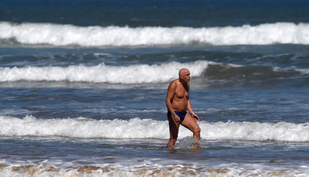 Un hombre se baña en la playa en Gijón