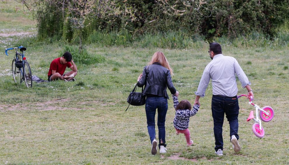 Unos padres pasean con su hija por un parque de Roma.