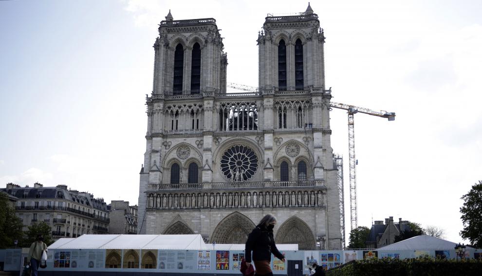 Una mujer pasa por delante de Notre Dame, la víspera de que se cumplan dos años del incendio.