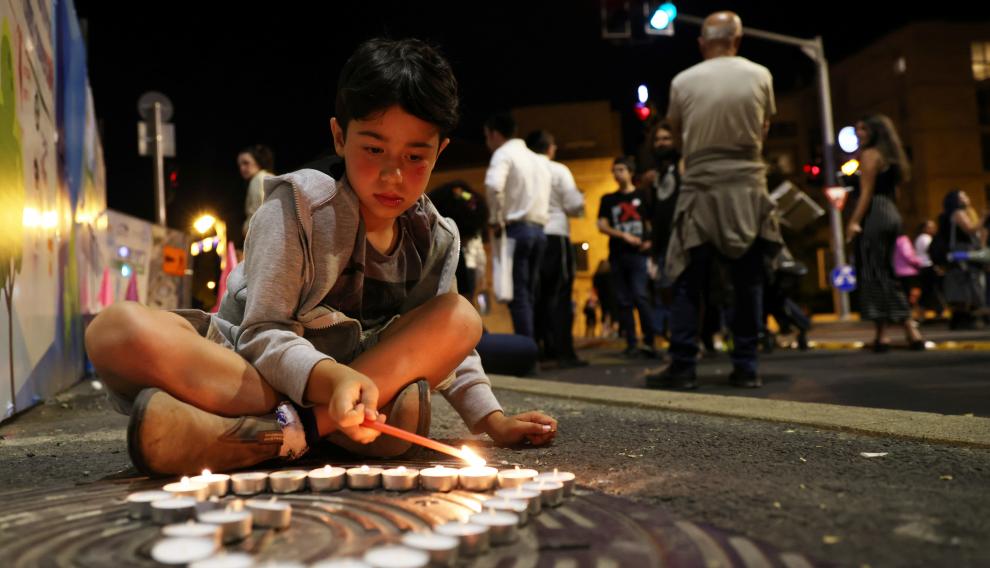 A boy lights candles during a vigil for the people killed and injured in a stampede at an ultra-Orthodox Jewish festival on the slopes of Israel's Mount Meron, in Jerusalem