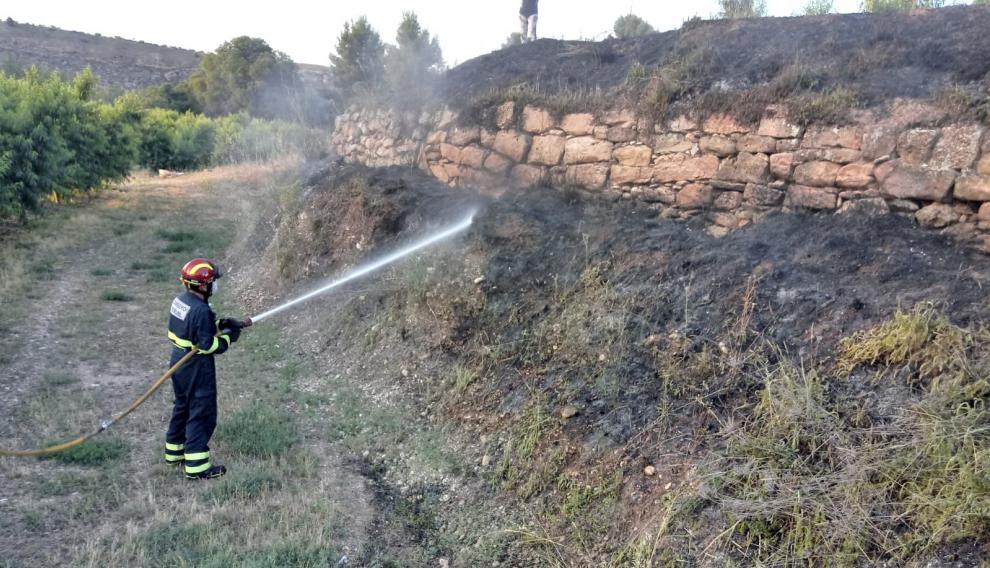 Los bomberos apagando el incendio registrado en un campo de cultivo yermo entre Calanda y Torrevelilla.