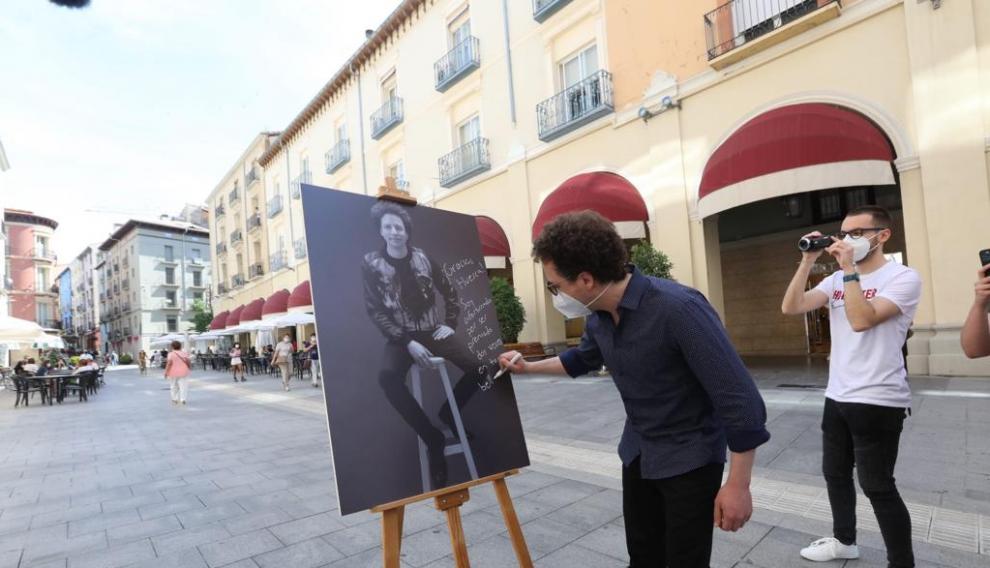 Michel Franco firma el póster con su retrato en los Porches de Galicia.