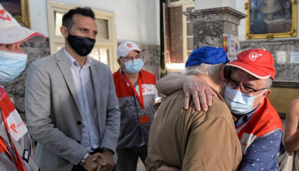 Abrazo entre un voluntario y un residente de Casa Amparo, ambos con mascarilla.