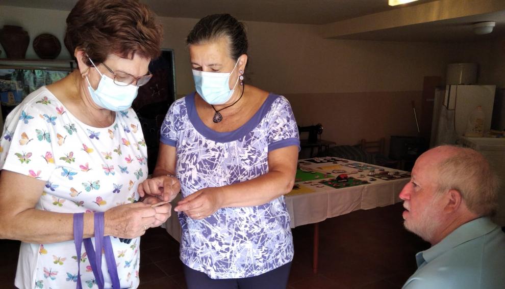 Carmen y su marido junto a una vecina de Bordón que recibe su 'còdol' solidario, tras la exposición que hicieron en verano.