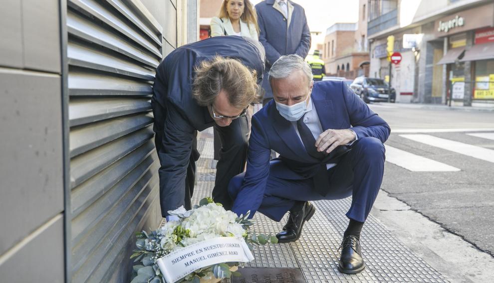 El presidente del PP de Aragón, Jorge Azcón, y Manuel Giménez Larraz, hijo del presidente del PP asesinado por ETA Manuel Giménez Abad, colocan un ramo de flores en el lugar donde la banda terrorista acabó con su vida en 2001.