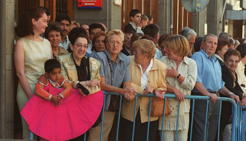 Un grupo de personas, entre ellas un niño vestido de torero, espera al entonces príncipe Felipe en una calle de Jaca.