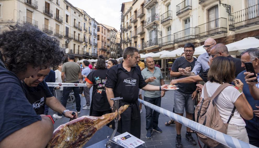 Un grupo de aficionados al corte despacha un jamón en la plaza del Torico e invita al público.