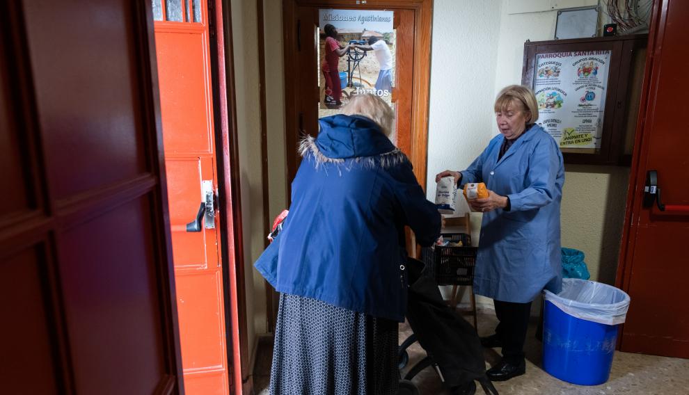 María Ángeles, voluntaria de la parroquia de Santa Rita (Agustinos), entrega una cesta de alimentos a Rosa, una usuaria de Zaragoza.