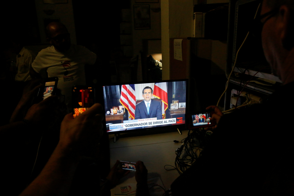 People in a conference room watch a television broadcast of Puerto Rico's governor Ricardo Rossello, as he resigns after days of protests calling for his resignation in San Juan, Puerto Rico July 24, 2019. REUTERS/Marco Bello [[[REUTERS VOCENTO]]] USA-PUERTORICO/