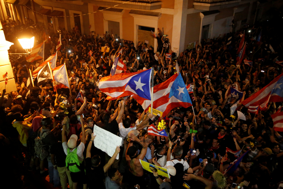 People in a conference room watch a television broadcast of Puerto Rico's governor Ricardo Rossello, as he resigns after days of protests calling for his resignation in San Juan, Puerto Rico July 24, 2019. REUTERS/Marco Bello [[[REUTERS VOCENTO]]] USA-PUERTORICO/