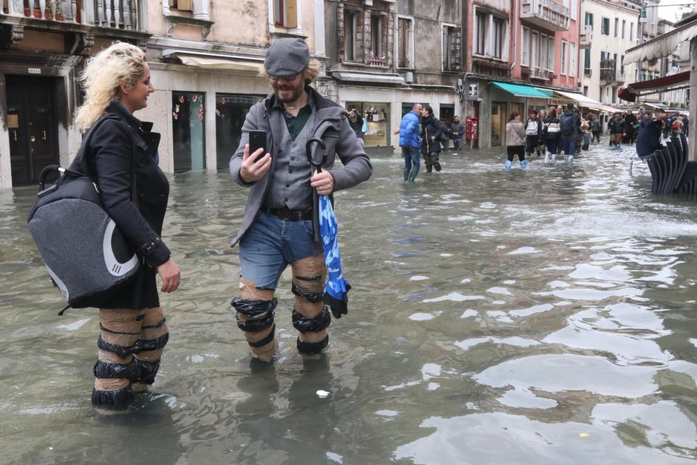 Venice (Italy), 17/11/2019.- Wearing either rubber boots, overknee waders, plastic overshoes or simply plastic bags wrapped and taped around their legs, tourists and residents resume their normal routine despite persistent flooding in Venice, Italy, 17 November 2019. High tidal waters returned to Venice on Saturday, four days after the city experienced its worst flooding in more than 50 years. (Italia, Niza, Venecia) EFE/EPA/EMILIANO CRESPI Aqua Alta in Venice