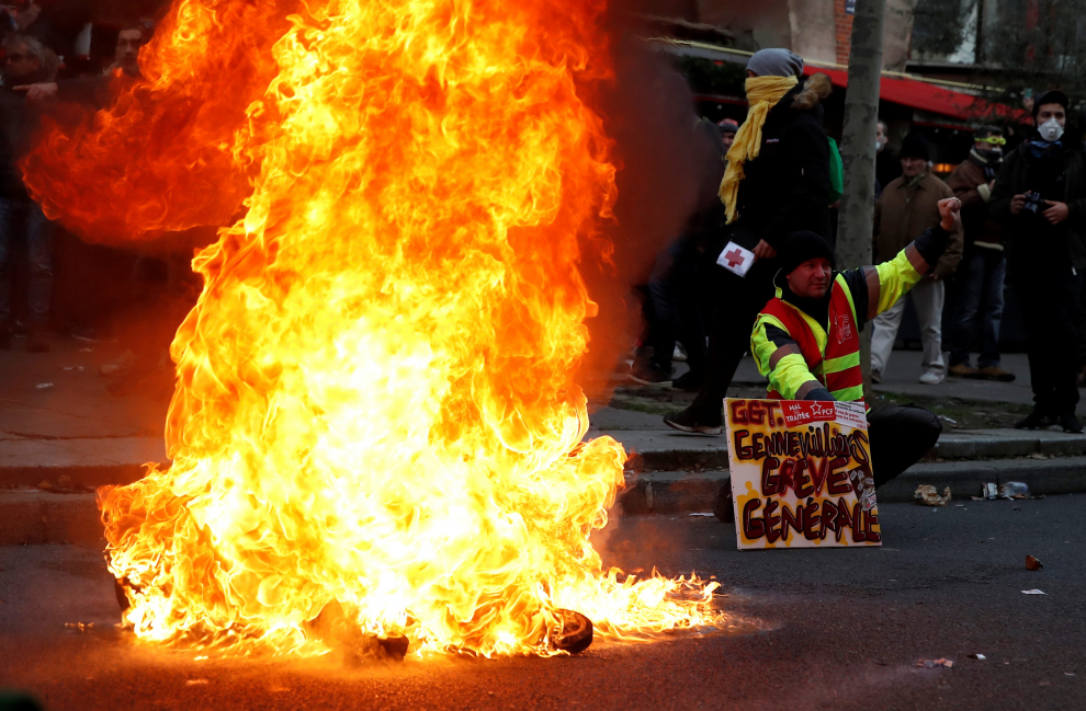 A protester sits next to a fire during a demonstration with French labour union members and workers as France faces its 38th consecutive day of strike against French government's pensions reform plans, in Paris, France January 11, 2020.  REUTERS/Gonzalo Fuentes [[[REUTERS VOCENTO]]] FRANCE-PROTESTS/PENSIONS