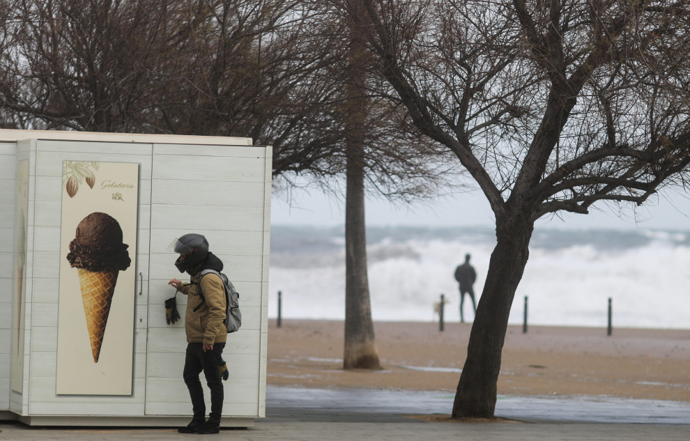 Un hombre se protege de la arena volando en un puesto de helados de la Barceloneta.