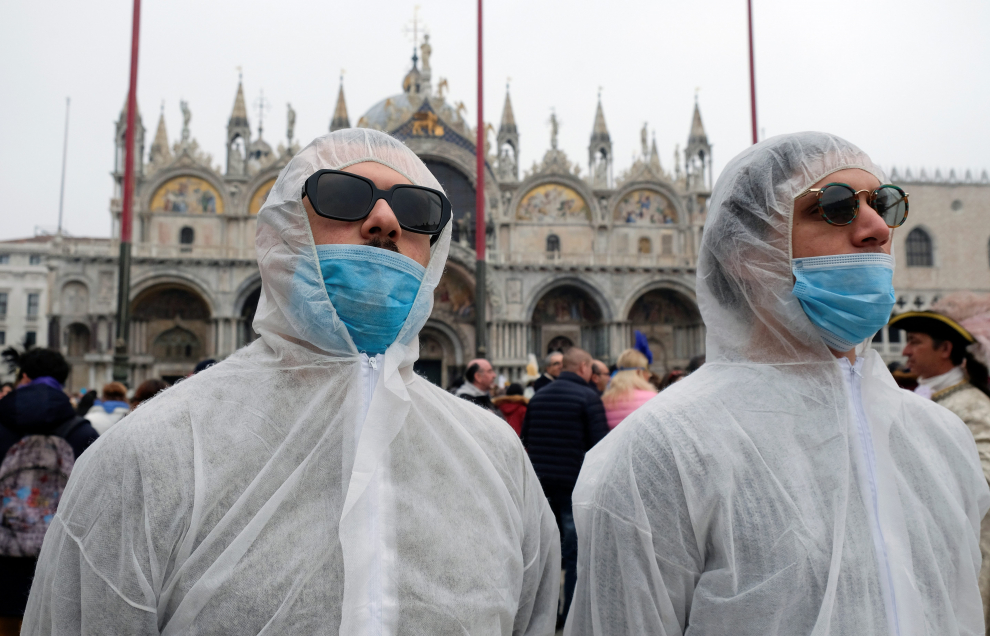 Police officers wearing protective face masks stand next to carnival revellers at Venice Carnival, which the last two days of, as well as Sunday night's festivities, have been cancelled because of an outbreak of coronavirus, in Venice, Italy February 23, 2020.  REUTERS/Manuel Silvestri [[[REUTERS VOCENTO]]] CHINA-HEALTH/ITALY-VENICE