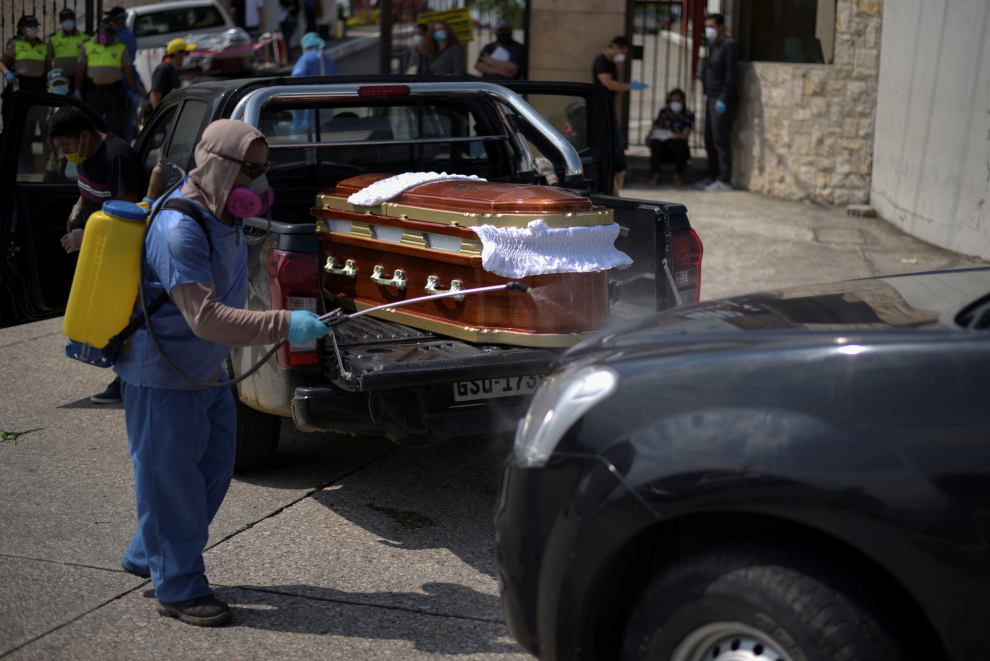 A worker sprays disinfectant on a vehicle carrying a coffin lined up to enter a cemetery as Ecuador's government announced on Thursday it was building a "special camp" in Guayaquil for coronavirus disease (COVID-19) victims, in Guayaquil, Ecuador April 2, 2020. REUTERS/Vicente Gaibor del Pino NO RESALES. NO ARCHIVES [[[REUTERS VOCENTO]]] HEALTH-CORONAVIRUS/ECUADOR