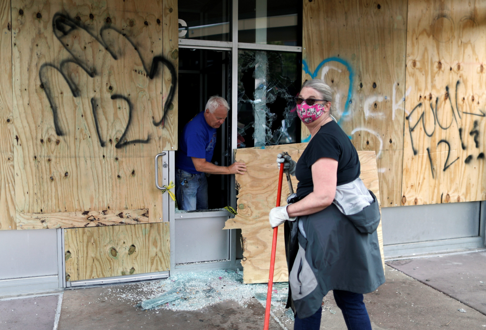 People clean up outside a local business in the area in the aftermath of a protest, in Minneapolis